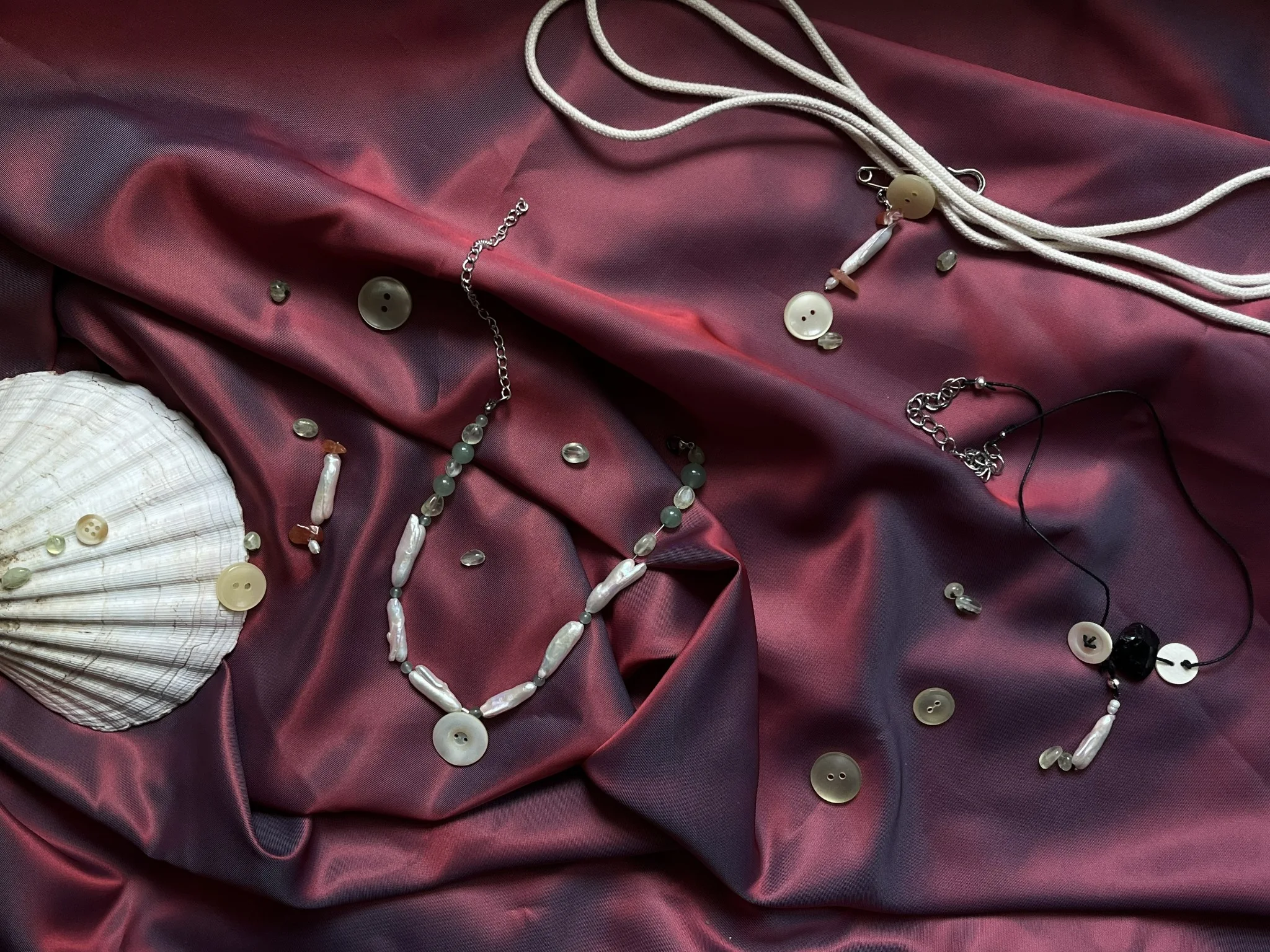 Kraken Pearl collection jewelry arranged on burgundy silk